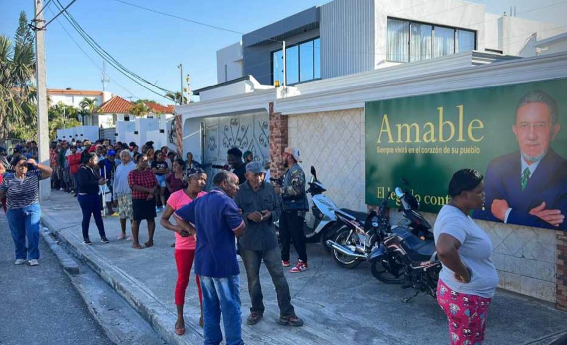 Grupo de personas se apostillan en casa de Amable Aristy para recibir bonos y canastas navideñas