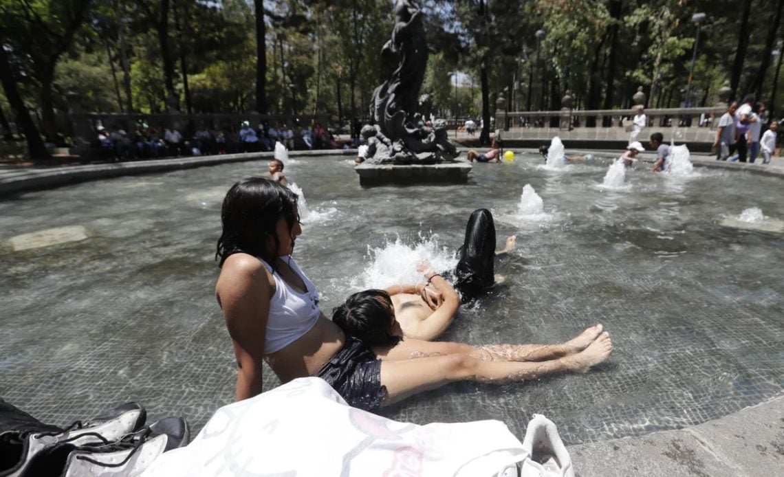 Mexicanos refrescándose en fuente de un parque