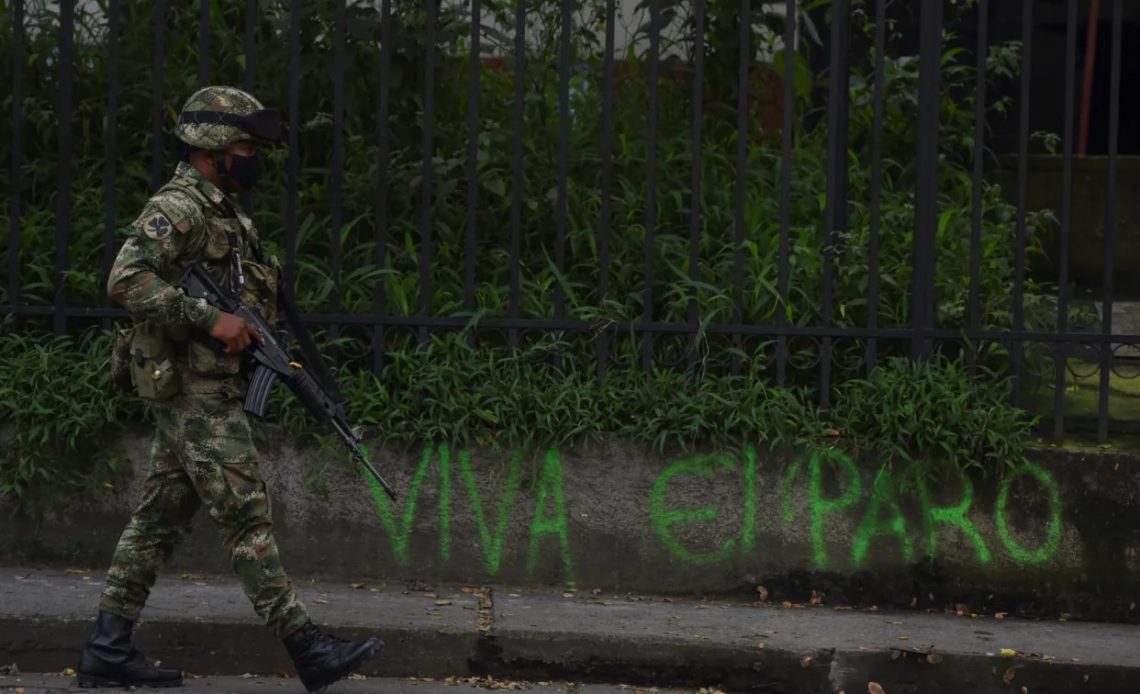 Militar colombiano frente a grafiti "Viva el paro"
